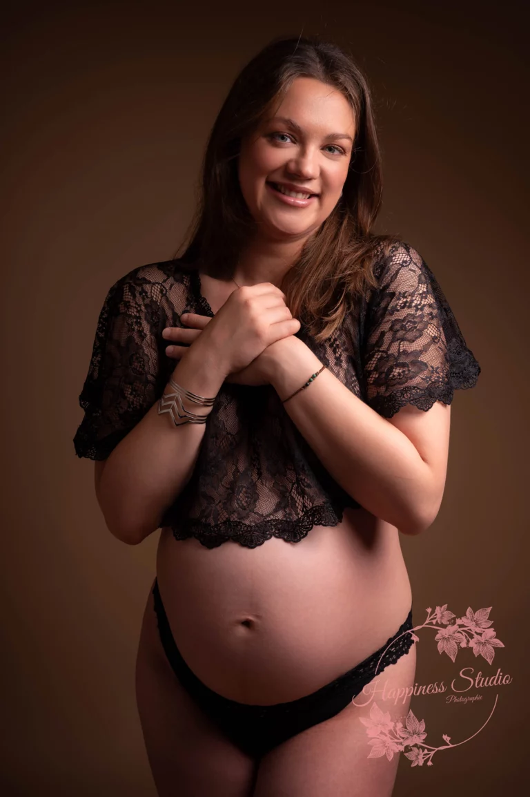 Future maman souriante pendant sa séance grossesse en studio