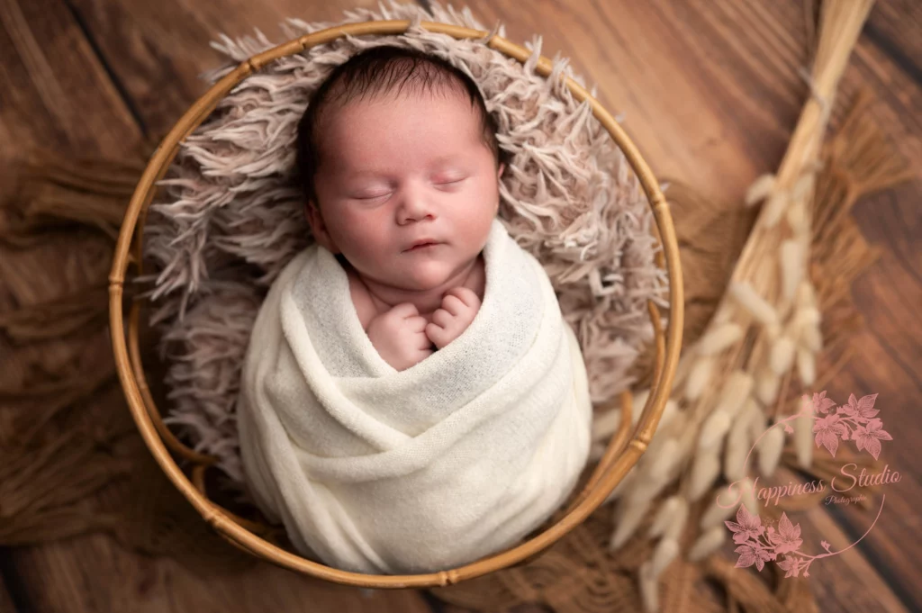 bebe emmailloté dans un petit décor studio photo